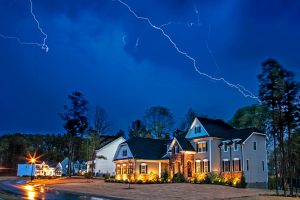 A bolt of lightning illuminates the night sky over a residential neighborhood.